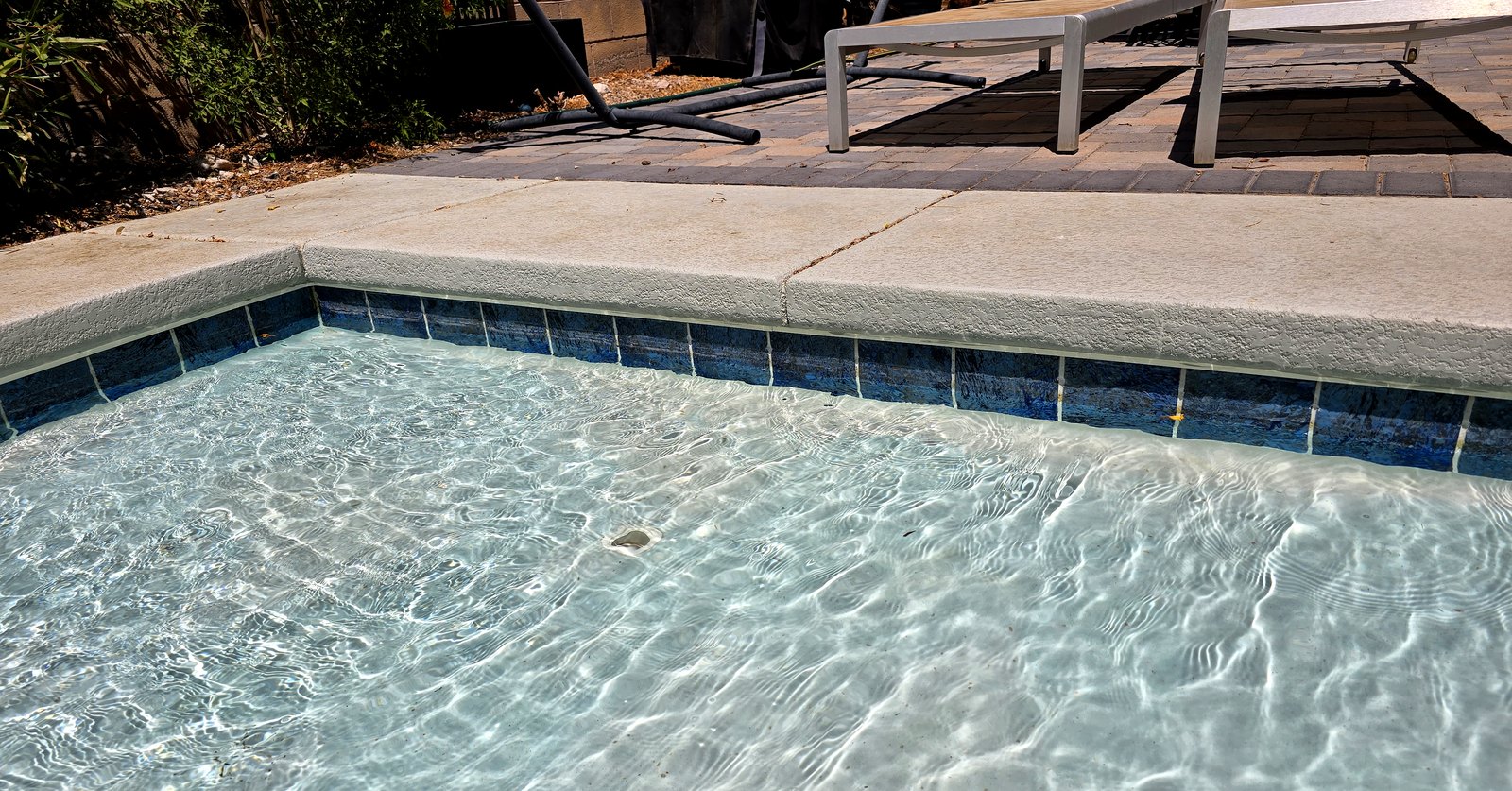 Pale calcium scale line along the waterline tile of a Las Vegas pool, left where hard water has evaporated and the minerals stayed behind